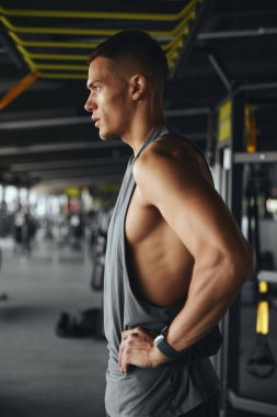 Dikey foto, yorgun erkek, nefes alıyor ve kalça üzerinde el ele tutuşuyor spor yaparken, antrenman yaparken ya da spor salonunda egzersiz yaparken. Vücut geliştirme, fitness ve sağlık hizmeti kavramı