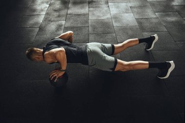 Modern jimnastik salonundaki yoğun spor sırasında güçlü bir adamın tek eliyle şınav çekmesi.