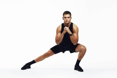 Enerjik erkek dinamik bir şekilde parlak bir stüdyo ortamında geriliyor, güç ve konsantrasyon sergiliyor, beyaz arka planda izole edilmiş. Fitness pazarlama ve reklam kampanyaları için ideal.