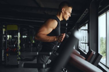 Ciddi atlet, paralel parmaklıklar üzerinde yoğun bir antrenmana hazırlanıyor. Spor salonundaki üst vücut ve çekirdek dengesini geliştirmek için güç, dayanıklılık ve kontrole odaklanıyor..