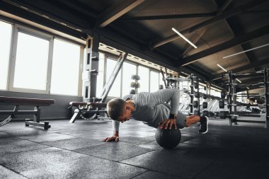 Fizikçi, modern spor salonunda yoğun spor yaparken tek eliyle spor yapıyor.