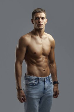 Moda stüdyosunda üstsüz poz veren atletik erkek, güç ve stili ön plana çıkarıyor. Fitness promosyonları ya da moda pazarlama kampanyaları için ideal.