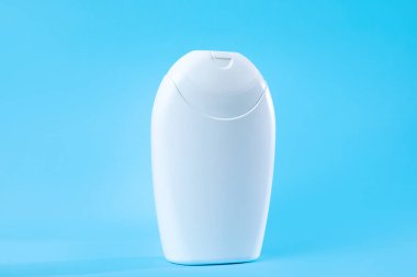 Işıl ışıl mavi bir arka planda sergilenen basit bir beyaz losyon şişesi. Güzellik ürünleri, kişisel bakım markalaşması veya minimalist tasarım kavramları için ideal.
