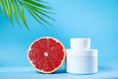 Taze bir greyfurt dilimi parlak mavi bir arka planda deri kaplarının yanında sergilenerek tazelik, canlılık ve doğal güzelliği çağrıştırıyor. Güzellik ve refah temaları için mükemmel.