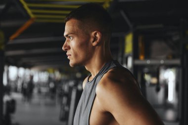 Dikiz aynasından ciddi bir şekilde konsantre olmuş bir adamın portresi, antrenmana ara verirken nefes almak, spor salonunda antrenman yapmak ya da egzersiz yapmak. Vücut geliştirme, fitness ve sağlık hizmeti kavramı