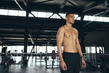 Spor salonundaki yoğun eğitimden sonra üstsüz erkek dinleniyor. Spor salonundaki eğitimden sonra yorgun adam dinleniyor.