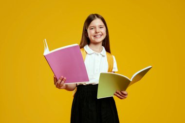 Mutlu bir çocuk coşkuyla renkli defterler tutarken aynı zamanda parlak sarı bir arka plana gülümsüyor ve öğrenmeye olan hevesini sergiliyor. Eğitim materyalleri ve okul promosyonları için ideal.