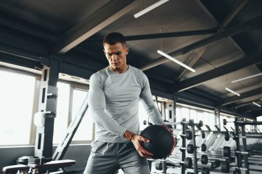 Spor salonunda tıp topuyla egzersiz yapan atletizm mankeninin yatay fotoğrafı. Genç güçlü adam spor yaparken spor topunu kullanıyor. Güç eğitimi, disiplin ve yaşam tarzı konsepti