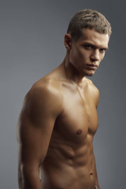 Formda bir erkek, iyi tanımlanmış kaslarını profesyonel bir stüdyo ortamında sergiliyor, dayanıklılık ve odaklanmayı somutlaştırıyor. Fitness pazarlama ve markalaşma materyalleri için ideal.