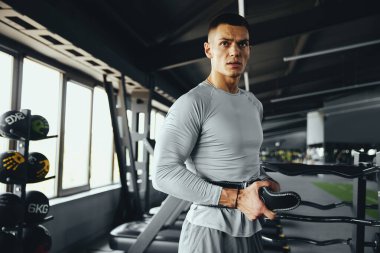 Adanmış sporcu, güçlü bir egzersiz rutini için uygun destek ve güvenliği sağlamak amacıyla deri kemerini ayarlar.