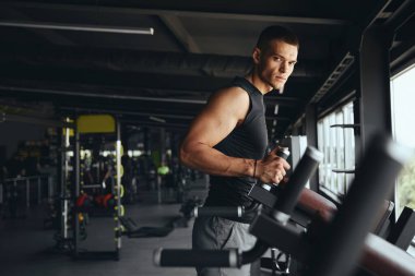 Odaklanmış ve kararlı olan yakışıklı vücut geliştirici paralel barlarda yoğun bir antrenman için hazırlanıyor. Spor salonundaki fiziksel sınırlarını test etmeye hazır..