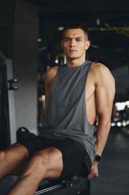 Kendini işine adamış bir sporcunun dikey fotoğrafı zorlu bir kürek çekme makinesinden sonra biraz soluklanıyor. Kararlı bakışı, eğitimindeki sıkı çalışma ve azmi vurgular.