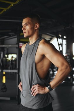 Spora, antrenmana ya da spor salonunda egzersiz yapmaya ara verirken kalça elele tutuşan yakışıklı bir adamın dikey foto görüntüsü. Vücut geliştirme, fitness ve sağlık hizmeti kavramı