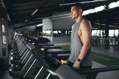 Koşu bandında yürüyen atletik adamın antrenman öncesi rutin egzersizi. Sportif erkek koşu pistinde yürüyor, spor kulübünde sağlık ve spor yapıyor..