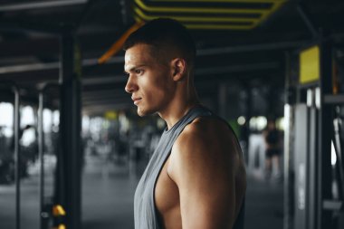 Spor salonundan sonra odaklanmış beyaz bir erkek sporcunun yan görüntüsü. Spor kıyafetleri içindeki spor eğitmeninin yatay fotoğrafı. Kameraya güven içinde poz veriyor..
