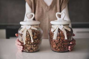 Bademli iki cam kavanoz tutan tanınmayan bir kız. Kavanozlar dantel fiyonklarla süslenir ve her mutfak dekoruna büyüleyici bir dokunuş eklenir. Sağlıklı gıda ve yaşam tarzı konsepti