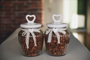 Bademlerle dolu iki cam kavanoz dantel yaylar ve kalp şeklinde kapaklarla süslenmiş büyüleyici ve zarif bir mutfak dekorasyonu yaratıyor..