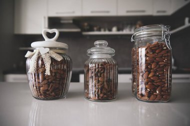 Bademlerle dolu üç cam kavanoz bir mutfak tezgahında güzelce oturur. Kavanozların dekoratif kapakları var ve mutfak düzenine biraz zarafet katıyor. Sağlıklı gıda ve yaşam tarzı konsepti