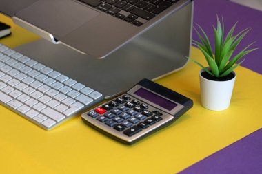 Office objects on a colorful background. Calculator and laptop. Calculations and accounting.
