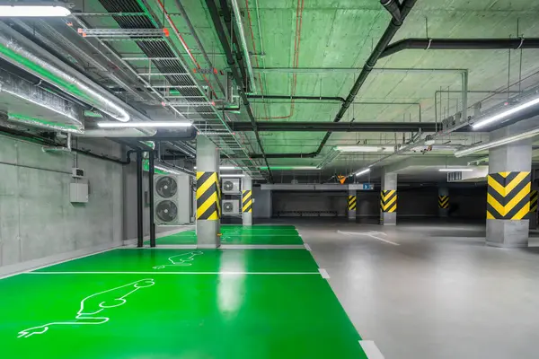 Empty underground parking lot with spaces for electric cars. Modern office building. Ecological transport