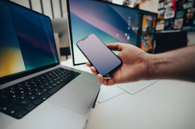 Ofis içi akıllı ekipman. El ele tutuşan telefon. Laptop bilgisayar görüntüsü. Boş ekran modellemesi.