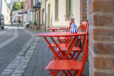 Restoran bahçe masası. Şehir sokağı. Kırmızı koltuk mavi bitki