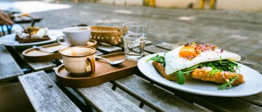Lokanta masasının dışında yumurtalı ve roket sandviçli waffle.
