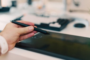 Grafik tasarımcı el dijital stil kalem grafiği tablet beyaz ışıklı ev aletleri tutuyor