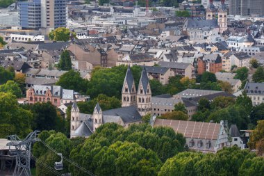 Koblenz Şehir Mimarisi Yeşil Ağaçlar Şehri Skyline. Almanya 'nın Koblenz kentinin yoğun manzarası, modern ve tarihi binaları yemyeşil ağaç tepe örtüleriyle harmanlıyor. Görüntü, kentsel planlama ve doğal yeşilliğin huzurlu bir arada yaşamasını yakalıyor.