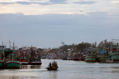 Bir balıkçı ve küçük bir balıkçı teknesi akşam balığından döndükten sonra marinadan geçiyorlar..