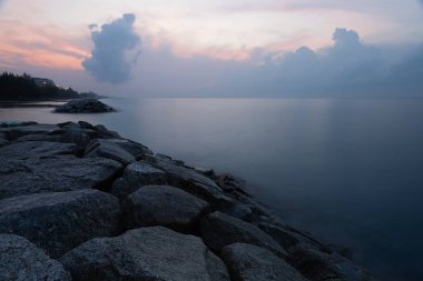 Sabahleyin deniz sakin ve pürüzsüz olduğunda kıyıdaki dalgalara dayanıklı kayalar..