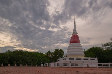 The white pagoda is tied with red and yellow cloth and the surrounding floor is paved with red bricks.
