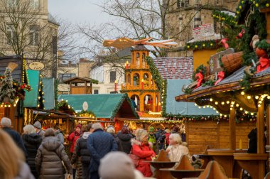 BONN, GERMANY - 6 Aralık 2022: Bonn 'da bir Noel pazarında kalabalık bir cadde ve arka planda Bonn Muenster' ın önünde çok katlı bir Noel piramidi var