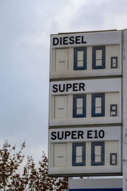 KOBLENZ, GERMANY - 22 Kasım 2022: Benzin fiyatlandırma ekranı kapalı ve kapalı bir benzin istasyonunda bulutlara ve arka planda bir ağaca karşı sıfır gösteriyor