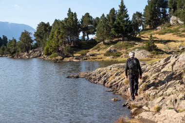 Hiker by a mountain lake in summer in Chamrousse in the Alps in France clipart