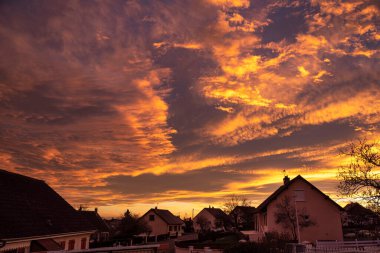 Sunset with clouds on a red sky over a village