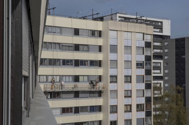 İskeledeki işçiler bir binanın tadilatını yapıyorlar.