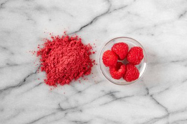 Kurutulmuş ahududu tozu ve yanında ahududu.