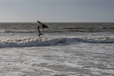 Denizde kanat çırpan bir insanın silueti.