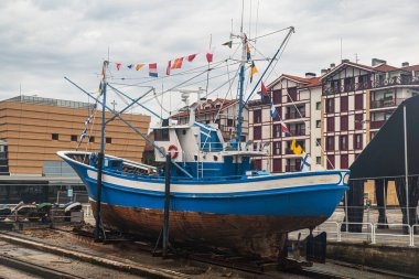 İspanya 'nın Irun şehrinde bir rıhtımda bayrakları olan mavi beyaz bir balıkçı teknesi.