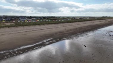 Fransa, Normandiya 'daki Gouville-sur-mer plajında renkli çatıları olan beyaz plaj kulübeleri.