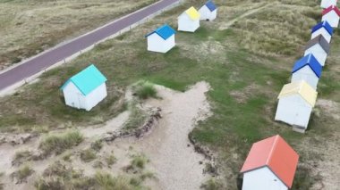Fransa, Normandiya 'daki Gouville-sur-mer plajında renkli çatıları olan beyaz plaj kulübeleri.