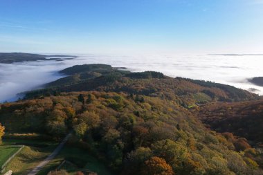 Fransa, Burgundy 'deki Morvan' daki Mont Beuvray 'in sonbahar renklerindeki ormanı ve vadilerdeki bulutları gösteren hava manzarası.