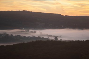 Fransa 'daki Şato-Chinon Şatosu' nda sonbahar manzarası, gündoğumunda ormanlar, tepeler ve evler