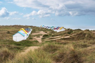 Fransa, Normandiya 'daki Gouville-sur-Mer' de renkli çatıları olan beyaz plaj kulübeleri.