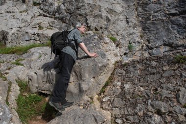 İspanya 'daki Cares Vadisi' nde kayalık uçurumları ve bitki örtüsüyle dağ yolunda bir yürüyüşçü.