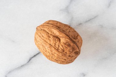 Close-up of walnuts in their shells on white marble