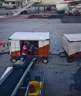 Kuala Lumpur, Malezya - 21 Aralık 2023: Havaalanı zemin ekibi pistte çalışmalarını sürdürüyor, bagaj taşıyorlar, yakıt ikmali yapıyorlar, uçak kontrolleri yapıyorlar.