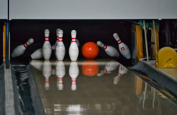Turuncu bowling topu ara sokakta beyaz lobutları deviriyor. Görüntü olmadan donmuş keskin hareket.