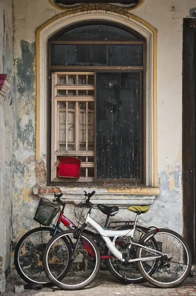 UNESCO 'nun dünya mirası olan Georgetown, Penang, Malezya' daki terk edilmiş bir sömürge tarzı peranakan mağazasının penceresinin altındaki paslı bisikletler..